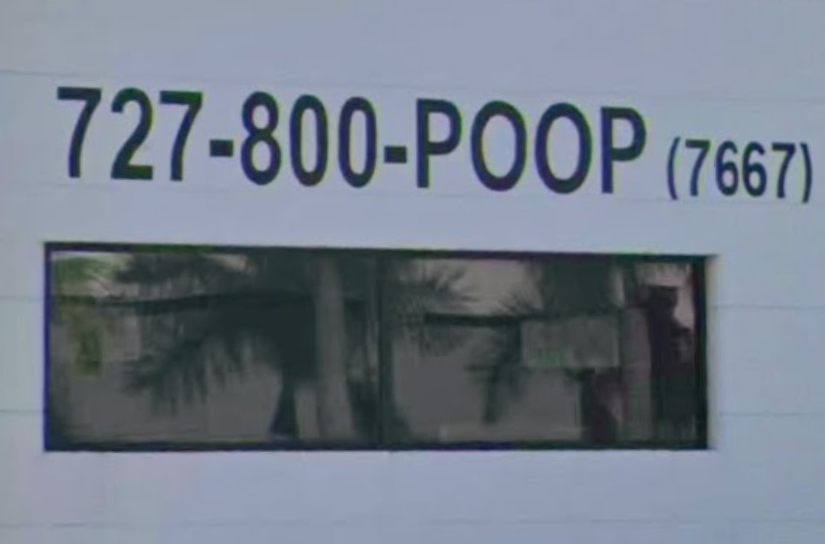 The 727-800-POOP sign above a window on the white plumbing business building.
